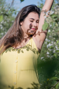 Portrait of young woman standing against plants