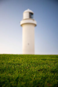 Lighthouse on field against clear sky