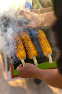 Close-up of man grilling corn