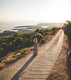 Woman standing on footpath against sky