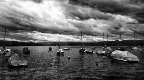 Boats in sea against cloudy sky