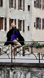 Full length of woman sitting against building