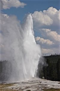 Geyser erupting against cloudy sky