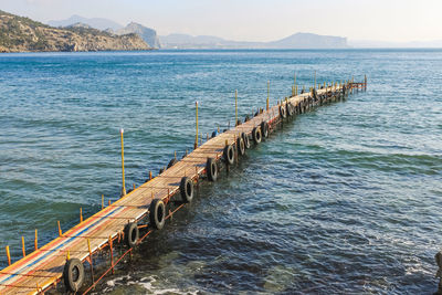 Wooden posts in sea against sky