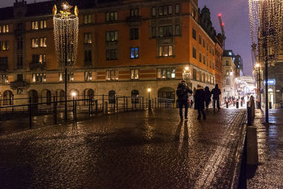 People walking on illuminated city at night