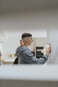 Side view of teenage using home automation through digital tablet mounted on wall