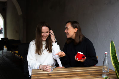 Two young women girlfriends communicate and have fun in a street cafe