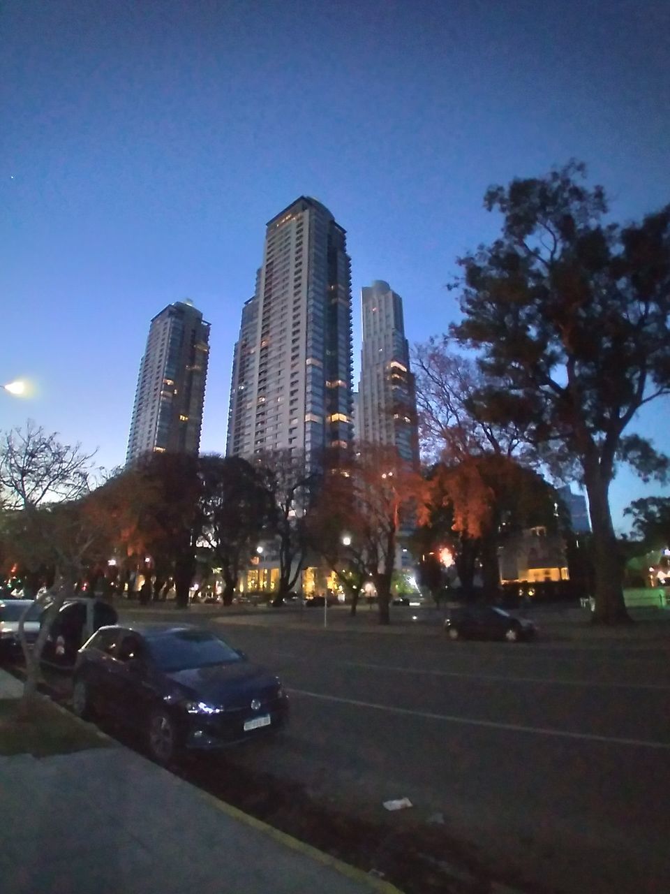 CITY STREET BY MODERN BUILDINGS AGAINST SKY IN BACKGROUND