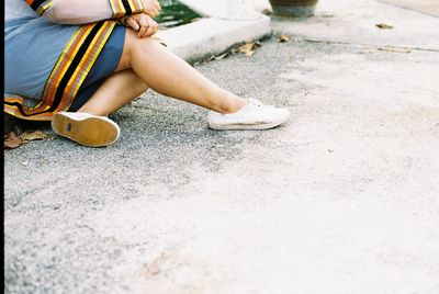 Low section of woman sitting on retaining wall