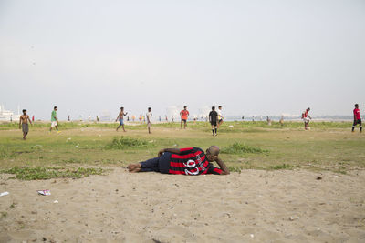 People on beach against clear sky