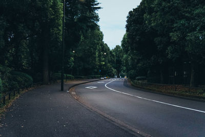 Empty road amidst trees against sky