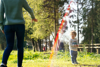 Rear view of mother playing with son at park