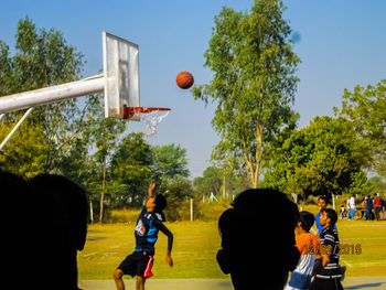 Rear view of man playing with basketball hoop