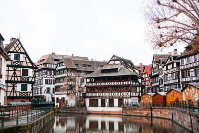 Buildings by river against sky in city