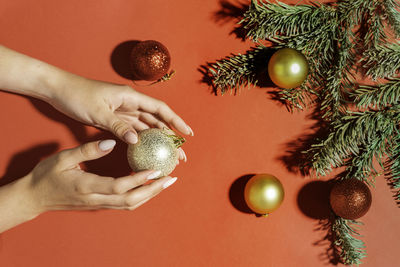 Beautiful hands on a red background with christmas tree branches and balls, hand care in winter