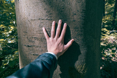 Midsection of person against tree trunk