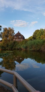 House by lake and buildings against sky