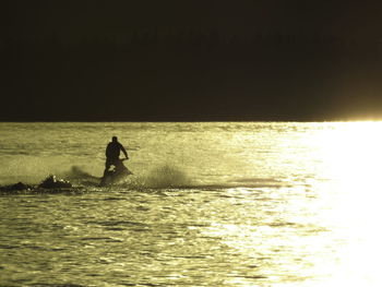 Silhouette man standing by sea against sky during sunset