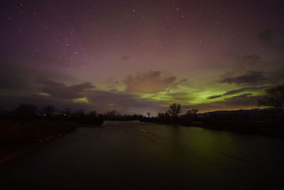 Aurora borealis lighting up the night sky over the madison river while reflecting off the water.