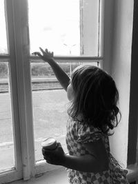 Rear view of woman looking through window