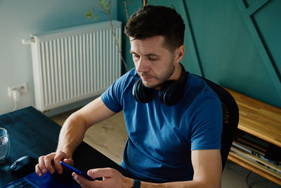 Bored man playing smartphone while working at home office