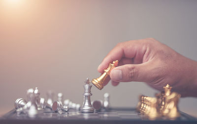 Cropped hand of man playing chess against gray background