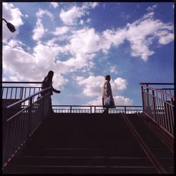 Low angle view of people against cloudy sky