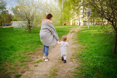 Mom and baby walk along the path in the park in the spring