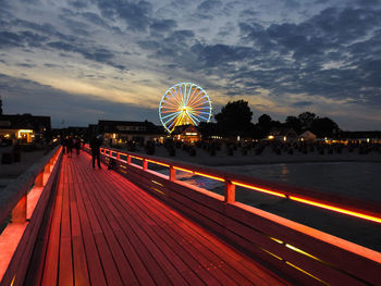 Illuminated ferris wheel against sky at night