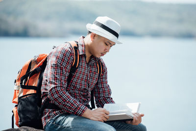 Midsection of man holding hat against bridge