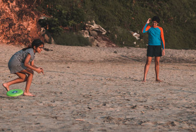 Siblings playing with plastic disc at beach