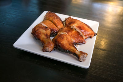 Close-up of grilled chicken legs on plate at table