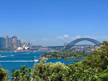 View of city at waterfront against blue sky