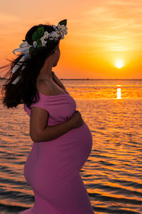 Woman standing by sea during sunset