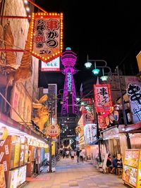 Illuminated street amidst buildings in city at night