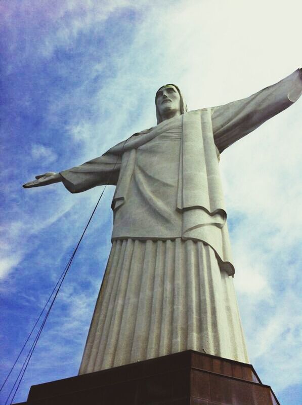 low angle view, sky, architecture, religion, built structure, building exterior, place of worship, spirituality, statue, sculpture, cloud - sky, human representation, church, cloud, art and craft, cross, art