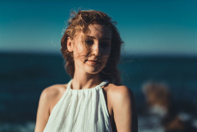 Close-up of young woman standing against sea