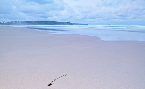 Scenic view of single foreground object on a beach against calm sky