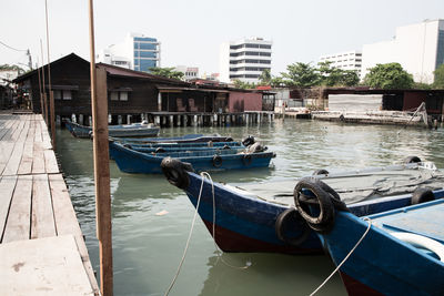 Boats moored in river by buildings in city