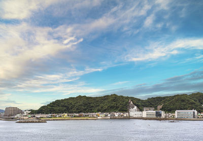 Scenic view of river by buildings against sky
