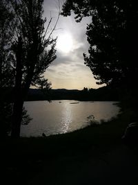 Silhouette trees by lake against sky during sunset