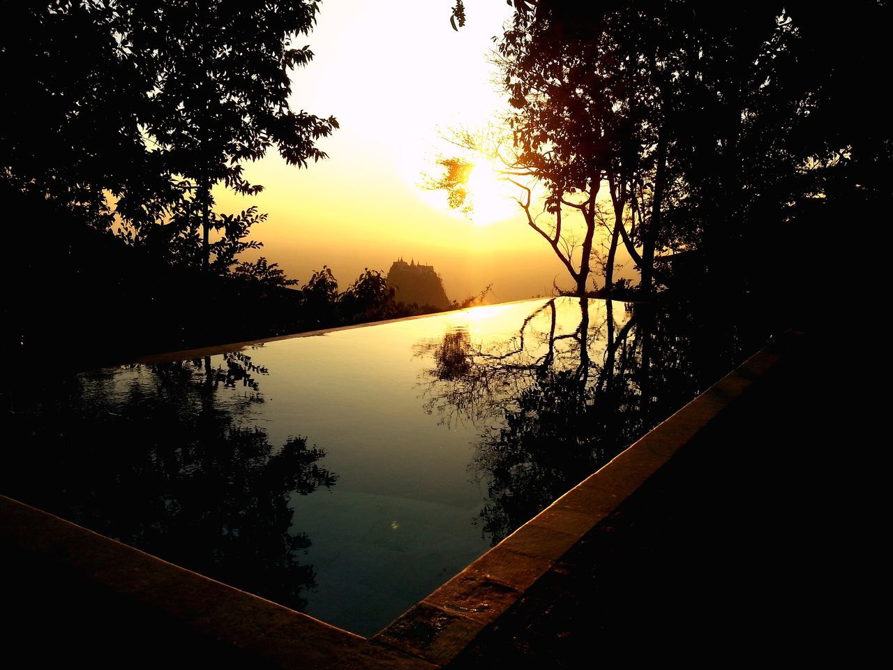 tree, water, tranquil scene, sunset, tranquility, lake, scenics, beauty in nature, silhouette, reflection, sky, nature, idyllic, sun, river, branch, mountain, non-urban scene, lakeshore, calm