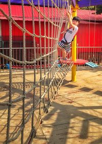 Girl climbing on rope on frame at park