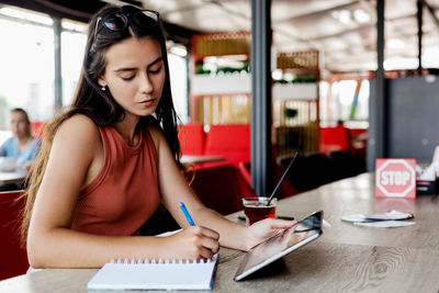 Portrait of a charming girl working or studying in a cafe., making notes in a notebook.