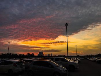 Cars on road against dramatic sky during sunset