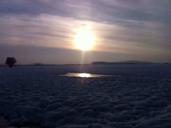 Sun shining through clouds over sea