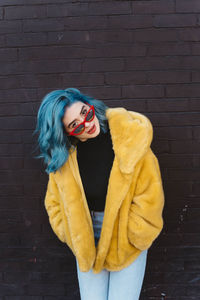 Portrait of woman standing against yellow wall