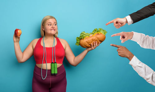 Young woman holding ice cream against blue background