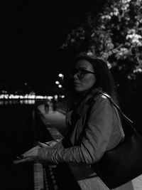 Young woman looking away while sitting outdoors