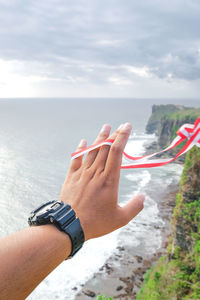 Midsection of person against sky holding indonesia flag